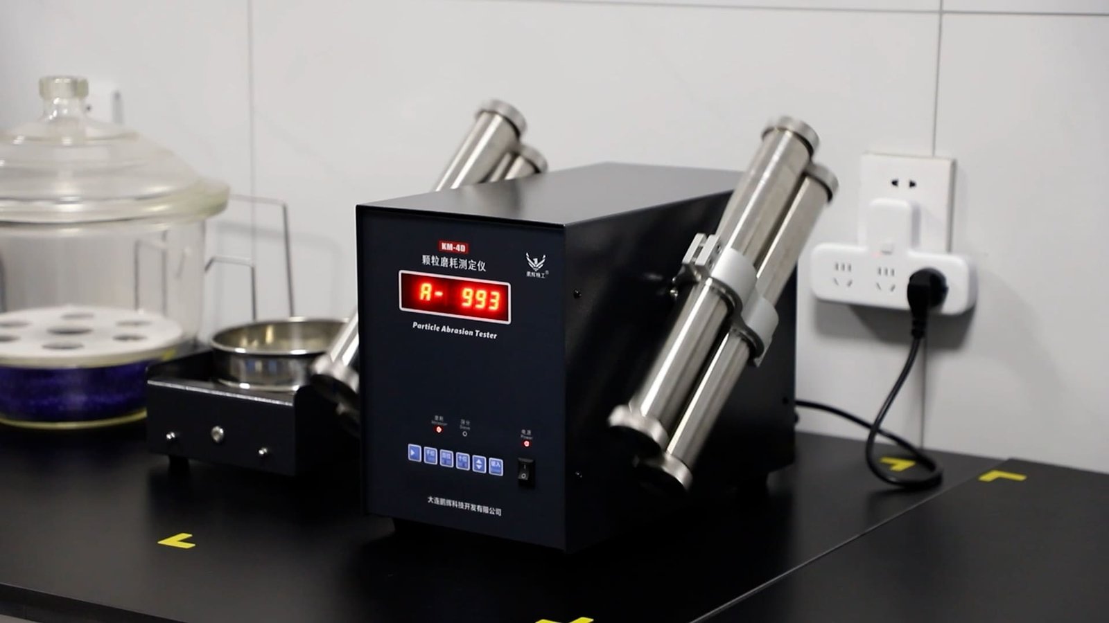 A laboratory technician operating an attrition testing machine